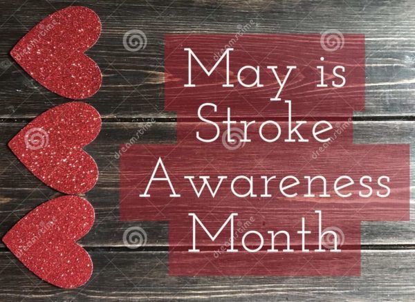 Red glitter hearts aligned on a dark wooden background beside the text 'May is Stroke Awareness Month' in white on red panels.